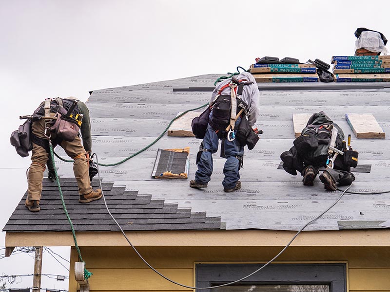 Roofers working on installing a new shingle roof.