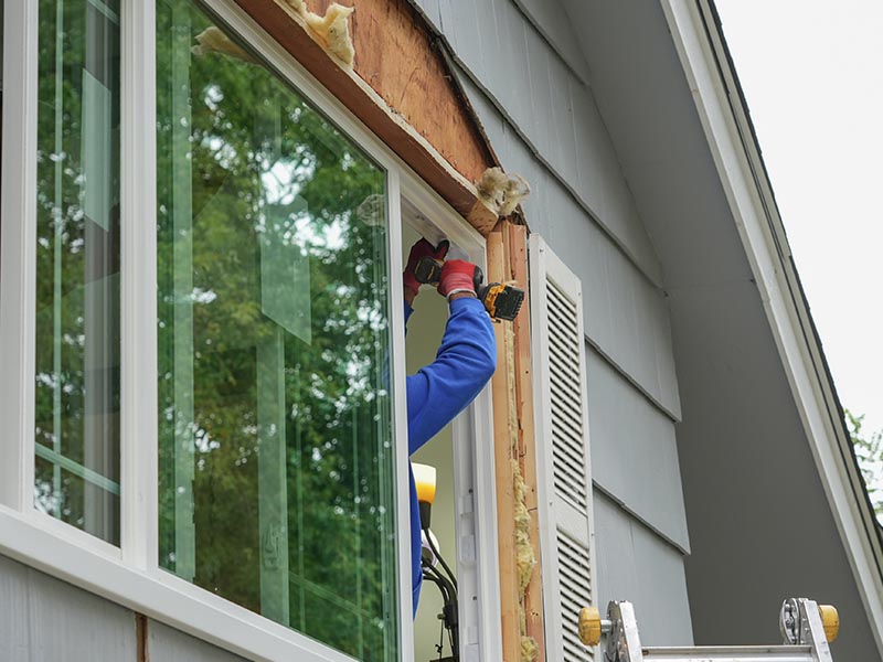 Contractor installing new windows on a residential house