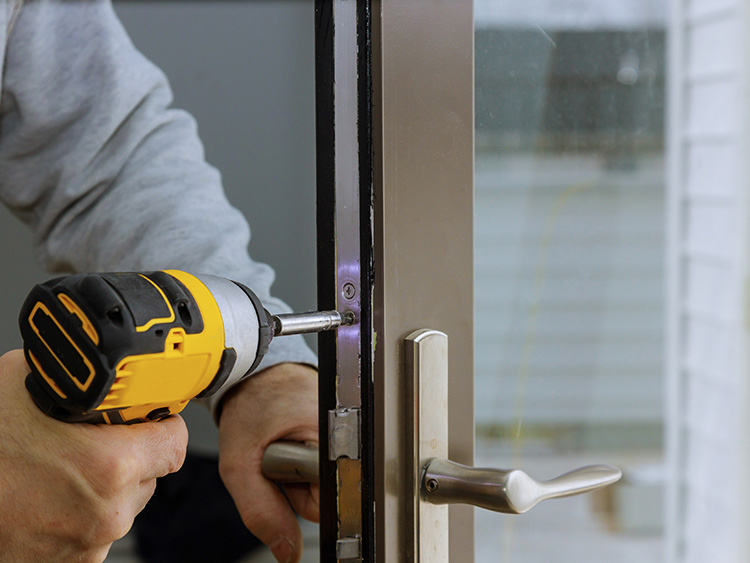 Contractor using drill to secure mortise plate to new exterior door.