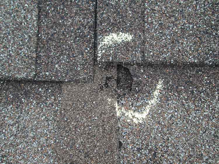 Closeup of damaged roof shingle from hail.