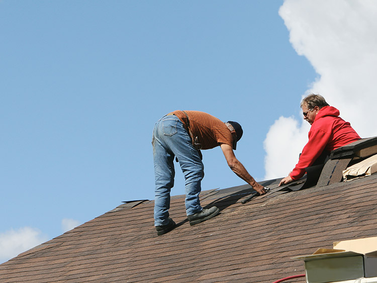 2 roofers inspecting residential roof for damage.