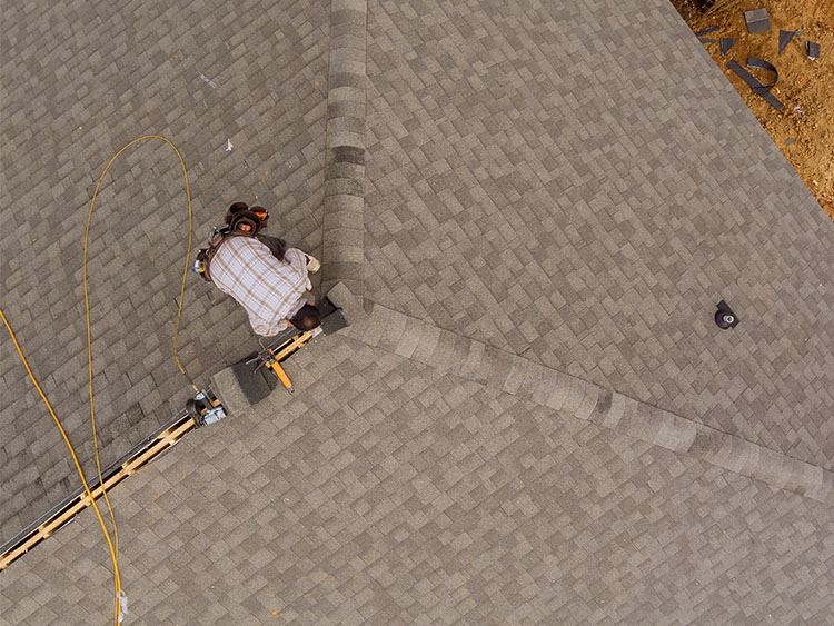 Arial view of roofer completing repairs on shingle roof.