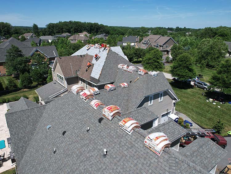AC Matthews crew working on roof with stacks of new shingles on top.
