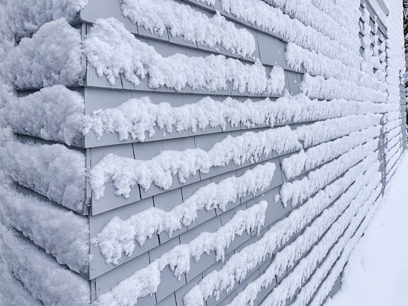 Cedar shake siding covered with snow.