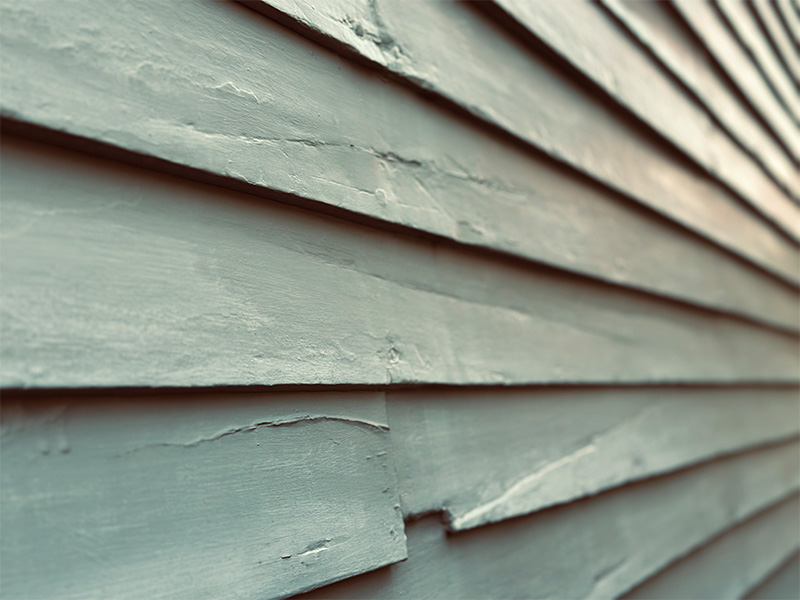 Aged and cracked green siding on a house.